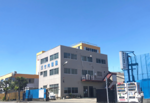 竹内建設の社屋外観の写真 青い文字で社名が書かれた3階建ての白っぽいビル